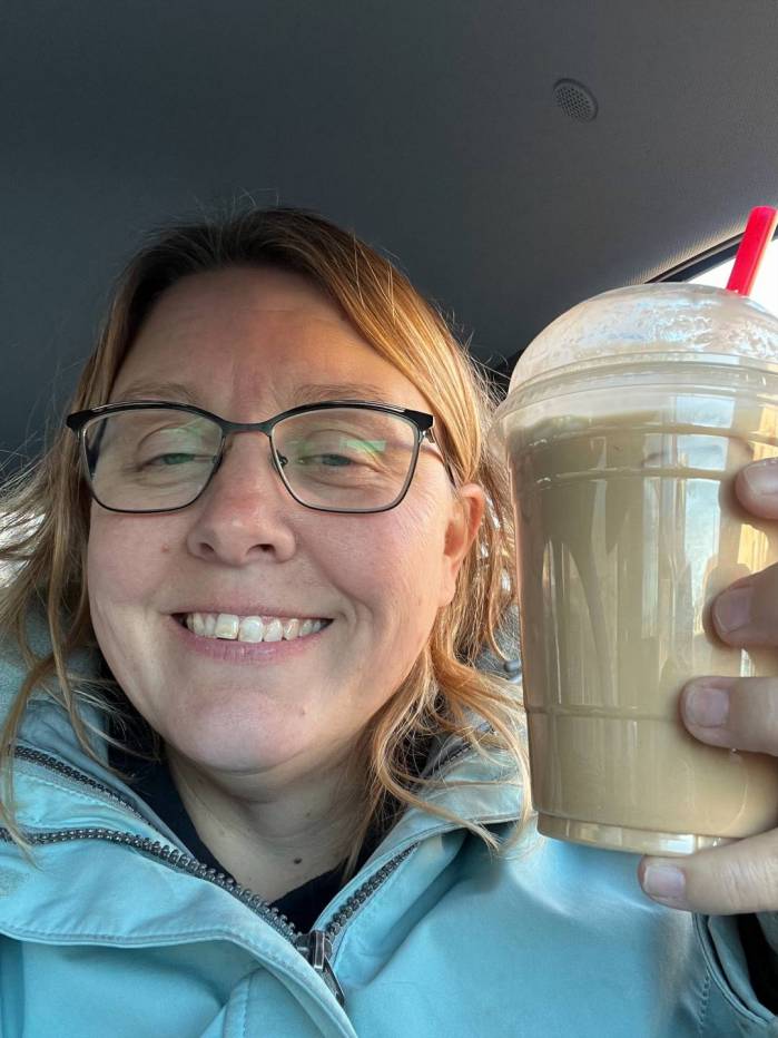 Erin holds a fancy coffee while sitting in a car.